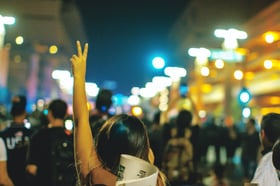 Woman with arm in air with peace sign